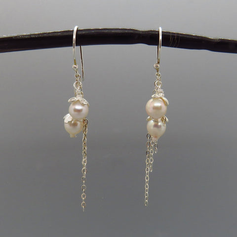 creamy white akoya pearls capped with silver flowers dangle on 3 rows of delicate silver chain   