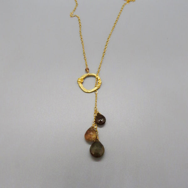 brown and copper faceted gemstones dangle from gold chain and slip through gold ring with three hearts on it lariat necklace