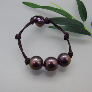 four black peacock pearls on dark brown leather cord bracelet with one pearl for toggle closure