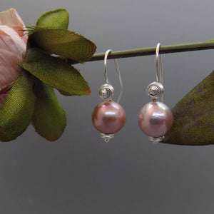 glowing lavender round pearls dangle from artisan swirl design ear wires.