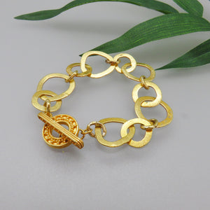 brushed gold plate sterling rings joined with gold links with granulated decorative toggle clasp.